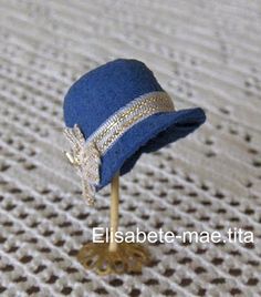 a small blue hat on top of a wooden stick with a diamond band around the brim