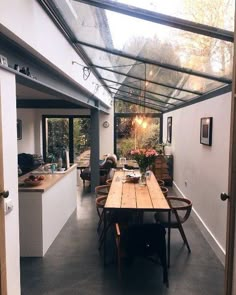 a long table sitting under a glass roof in a kitchen next to an open door