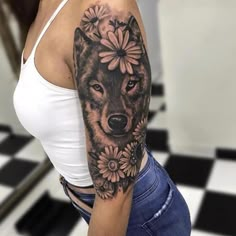 a woman's arm with a wolf and flowers tattoo on the left side of her body