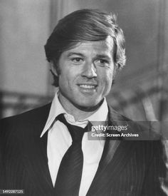 an old black and white photo of a man in a suit smiling at the camera