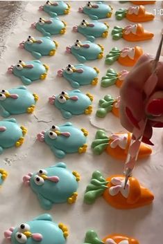 someone is decorating some little blue and orange animals on a sheet of white paper