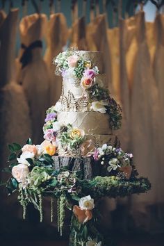 a three tiered cake with flowers and greenery on top