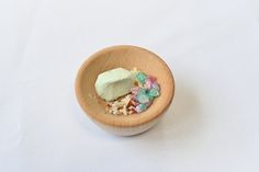 a small wooden bowl filled with marshmallows and candies on a white surface