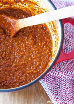 a pot filled with chili sauce and a wooden spoon