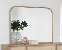 a wooden dresser with a mirror and vase on it