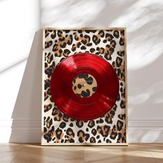 a red vinyl record sitting on top of a leopard print wallpaper next to a white wall