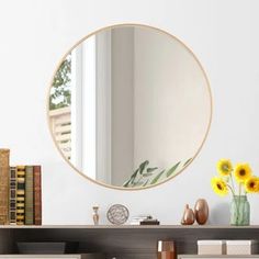 a mirror sitting on top of a wooden shelf next to a vase filled with flowers