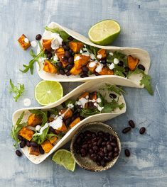 three tacos with black beans, avocado and cilantro on top