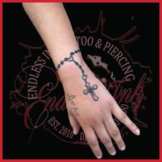 a person's hand with a cross tattoo on it and a chain around the wrist