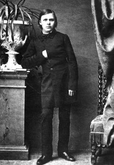 an old black and white photo of a young man standing in front of a table