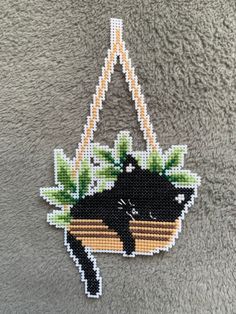 a black cat is sitting in a hammock with green leaves on the side