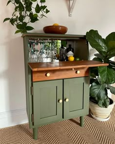 a green cabinet sitting next to a potted plant on top of a carpeted floor