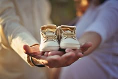 two people holding out their shoes in the palm of their hands while wearing white clothes