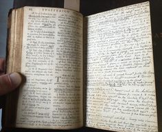 an open book with writing on it being held by a person's left hand