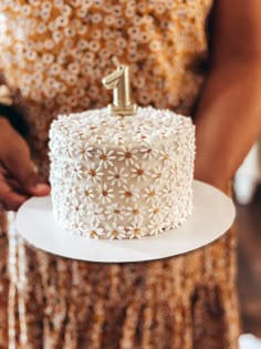 a close up of a cake on a plate with a person holding it in the background