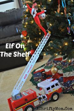 the elf is on top of the firetruck next to the christmas tree and presents