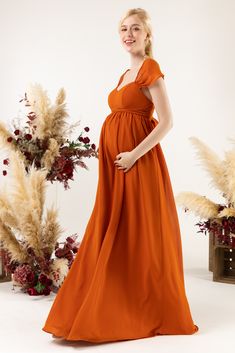 a pregnant woman in an orange dress poses for a photo