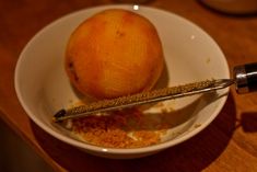 a bowl filled with oranges and spices on top of a wooden table next to a bottle