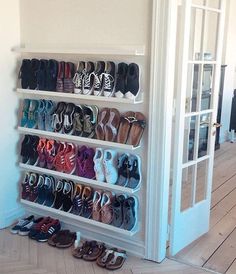 there are many pairs of shoes on the floor in front of an open closet door