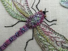 a close up of a dragonfly on a piece of cloth with bead work