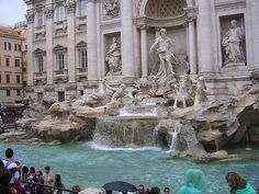 the fountain is surrounded by statues in front of an ornate building with columns and arches