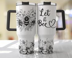 two travel mugs with the words let it bee printed on them, sitting next to each other