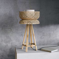 a wooden stool sitting on top of a white table next to a book and lamp