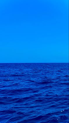 an airplane flying over the ocean on a clear day with blue sky in the background