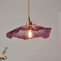 a pink flower hanging from a light fixture