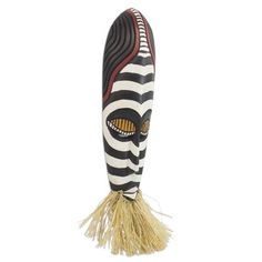 an african mask hanging from the side of a white and black wall mounted decoration with yellow fringes