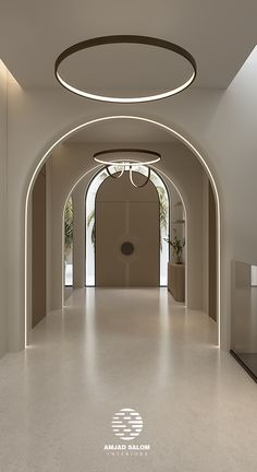 an empty hallway with white walls and lights on the ceiling is lit by recessed lighting