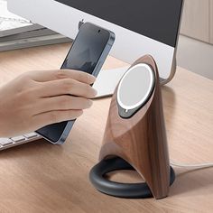 a person is using their cell phone to charge an electronic device on a desk next to a computer