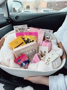 a person holding a basket filled with lots of items in the back seat of a car