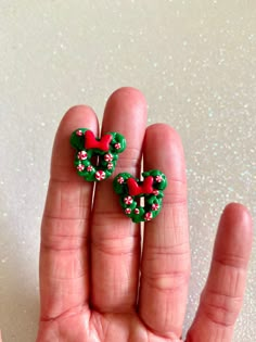 someone is holding two small christmas bows in their hand and they are both wearing red, white and green beads