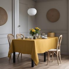 a dining table with yellow linens and plates on it