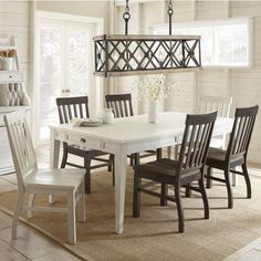 a dining room table and chairs in front of a window with white paint on the walls