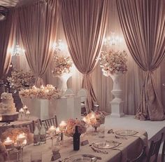 a table set up for a wedding reception with candles and flowers on the tables in front of it