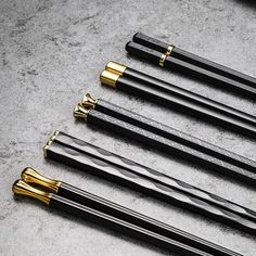 five black and gold pens lined up on a gray surface with one pen in the middle