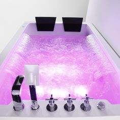 a bathtub with three faucets and two soap dispensers in it