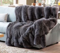 a couch covered in grey fur sitting on top of a wooden floor