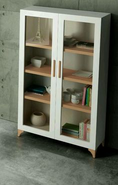 a bookcase with two doors and shelves on each side, in front of a concrete wall