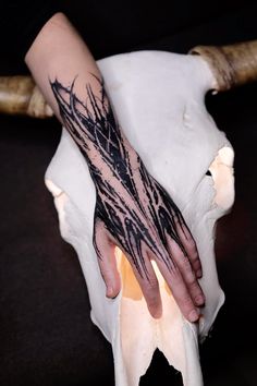 a person's hand with black ink on it next to a white animal skull