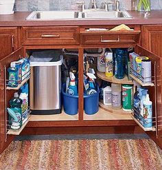 an open cabinet in the middle of a kitchen filled with cleaning products and other items