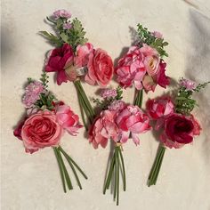 pink and red flowers are arranged on a white surface