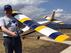 a man standing next to a yellow and blue plane