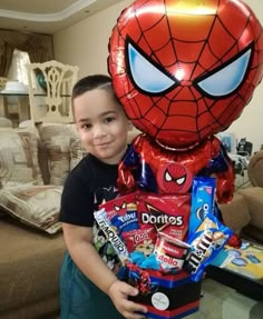 a young boy holding a spiderman balloon and candy