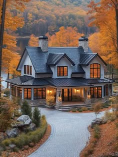 a large white house surrounded by trees with fall leaves on the ground and foliage around it