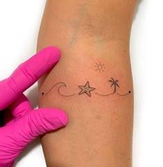 a woman's arm with a star and palm trees tattoo on her left side