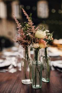 three vases filled with flowers on top of a wooden table