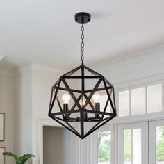 a chandelier hanging from the ceiling in a dining room with white walls and windows